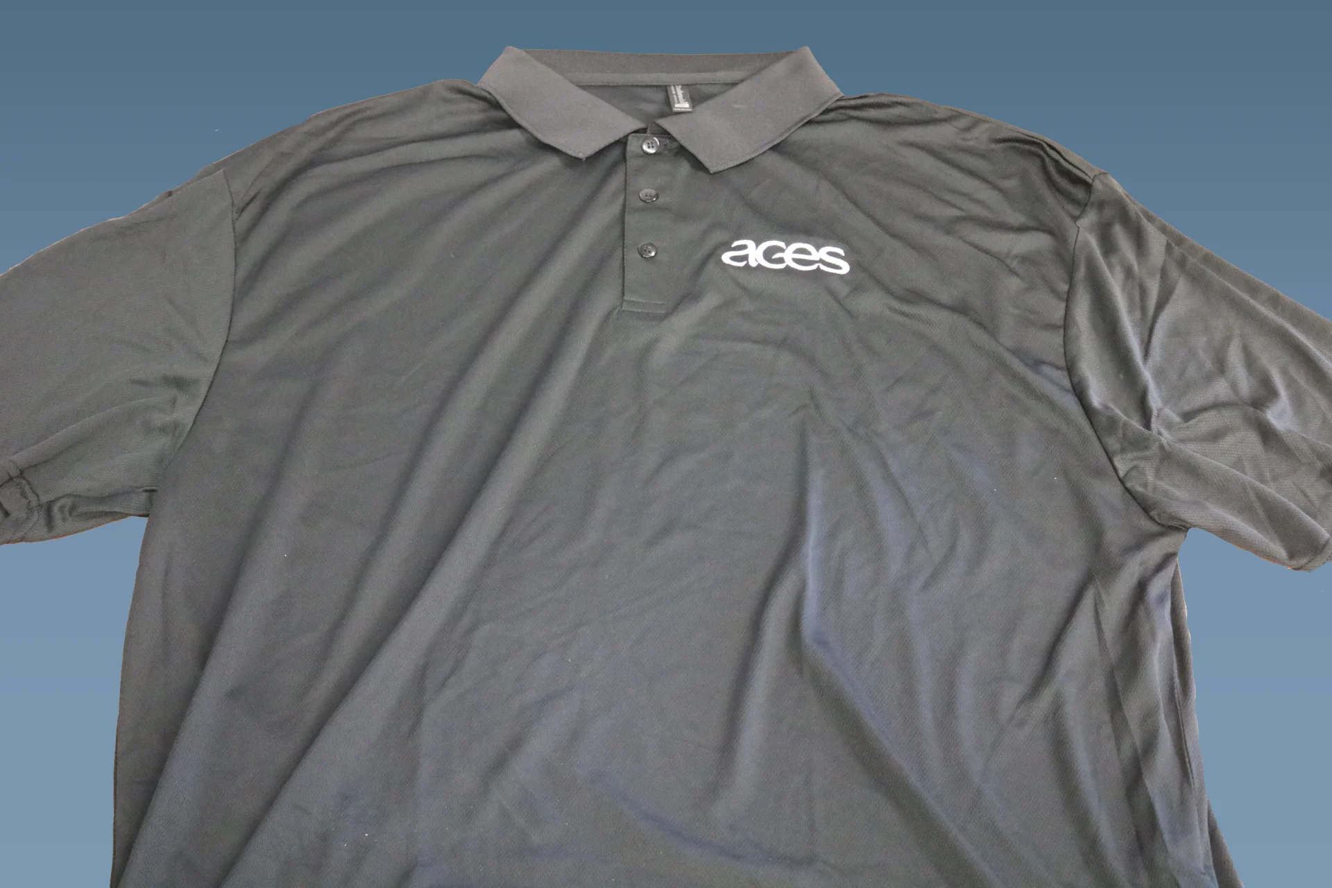Black polo shirt with white ACES logo